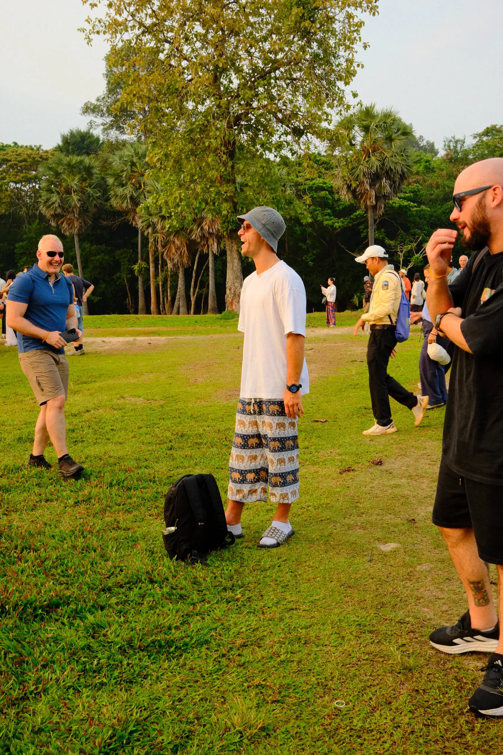 Un grupo charlando de pie en un parque, al atardecer, cerca de Angkor