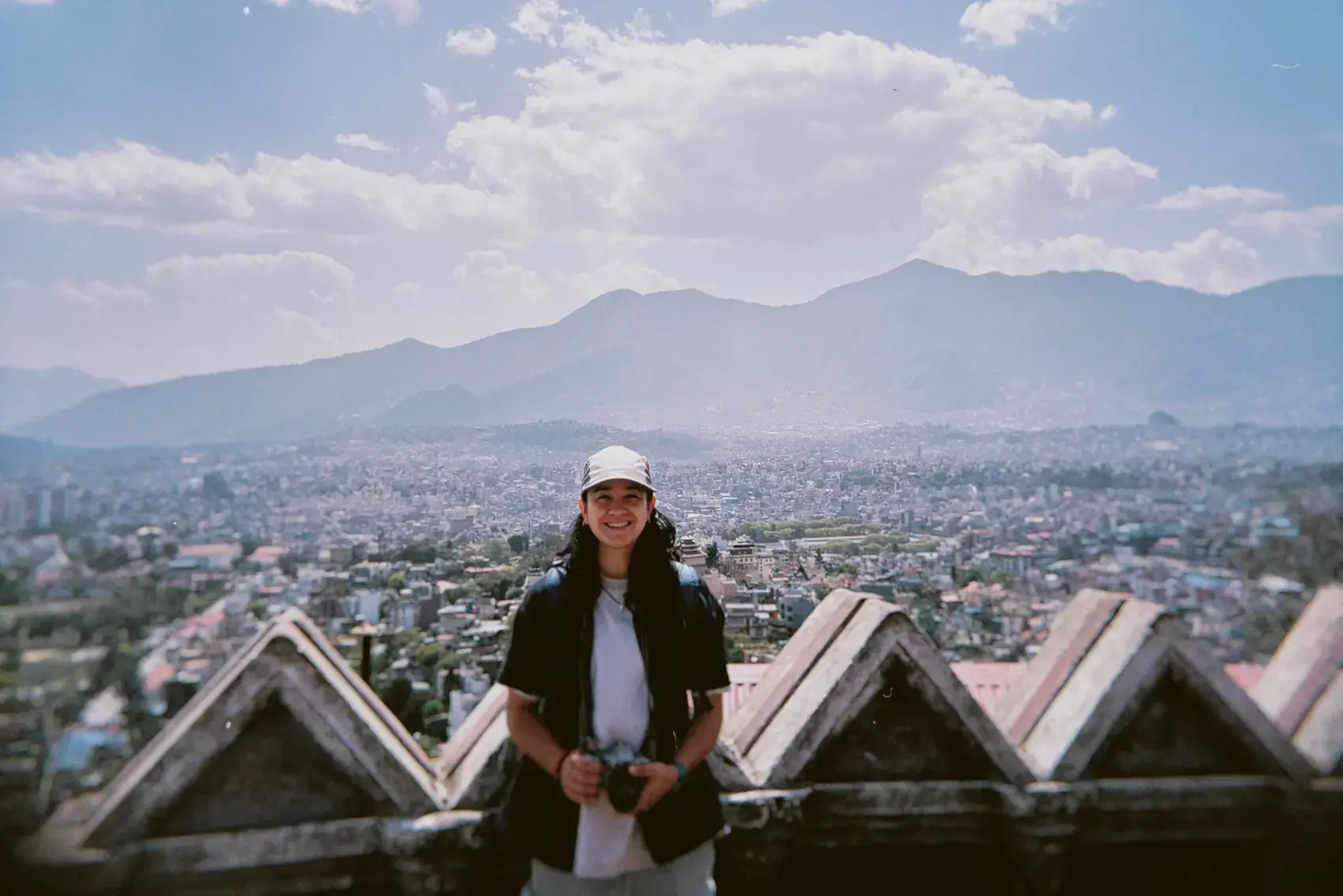 Una viajera en un mirador, con los techos de teja y la ciudad abajo